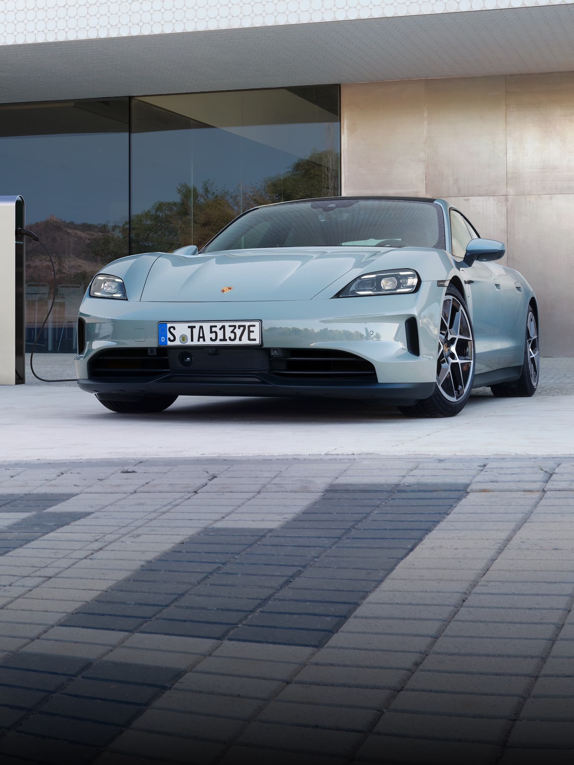 A Porsche Taycan parked outside in front of a modern building.